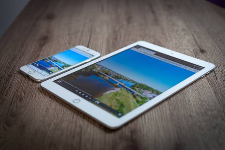 iPad and iPhone showing a scenic landscape on a wooden table, highlighting portability and technology.