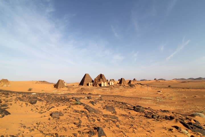 Ancient Meroe pyramids stand in the arid desert under a clear sky, showcasing Sudan's rich history.