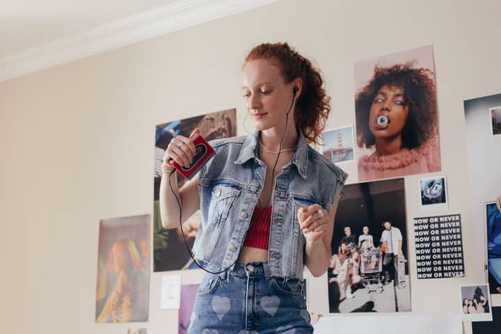 Woman enjoying music with a retro cassette player and earphones, embracing 90s style.