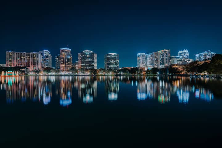 Stunning nighttime view of Orlando's illuminated skyline reflecting in a calm body of water.