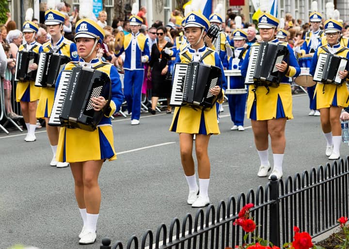 Vibrant street parade featuring musicians in colorful uniforms playing accordions.
