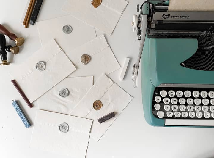 Overhead view of a vintage typewriter with wax-sealed envelopes, evoking a classic writing theme.