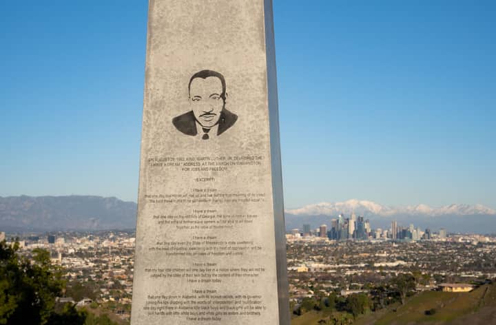 Martin Luther King Jr. monument overlooking Los Angeles skyline with mountain backdrop.