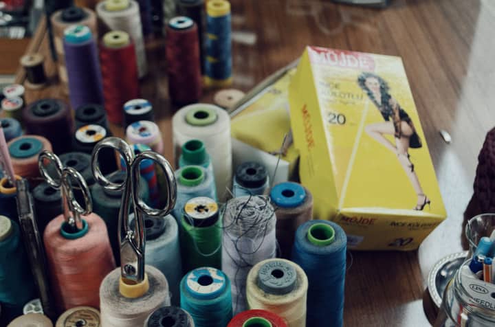 A vibrant collection of sewing threads and scissors on a craft table in İzmir, Turkey.