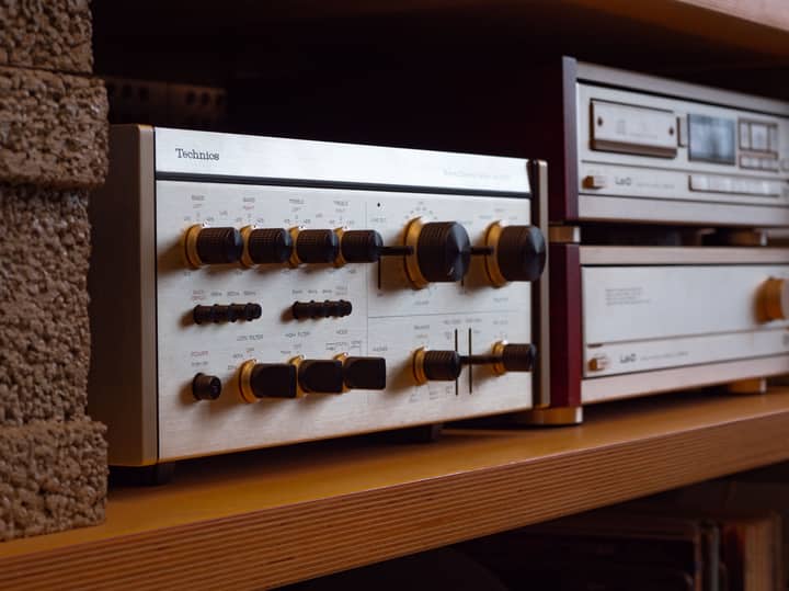 Close-up of a retro stereo receiver with knobs on a shelf, exuding nostalgic vibes.