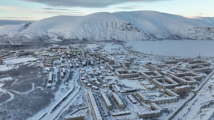 Aerial view of Kirovsk, Russia, showcasing snow-covered town and mountains in winter.