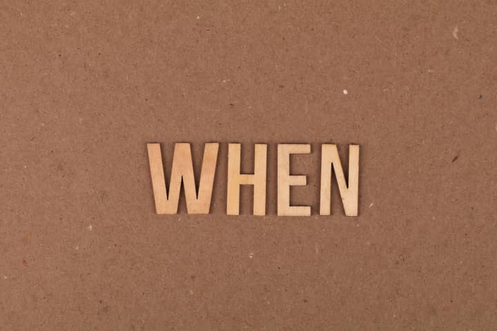 Wooden letters forming the word 'When' on a plain cardboard background.