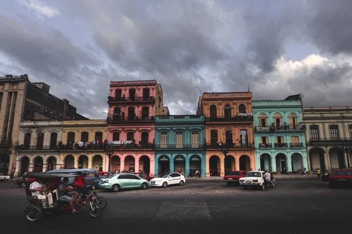 Vibrant colonial buildings in Havana under a moody sky with street activity.