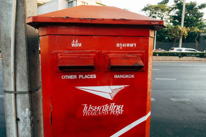 Bright red Thailand post box on a street in Bangkok, capturing urban life.