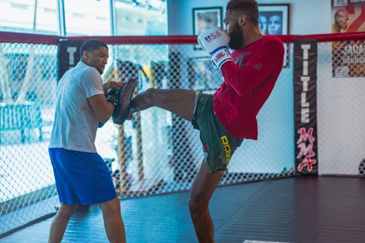 Dynamic kickboxing training session featuring two athletes in action inside a gym.