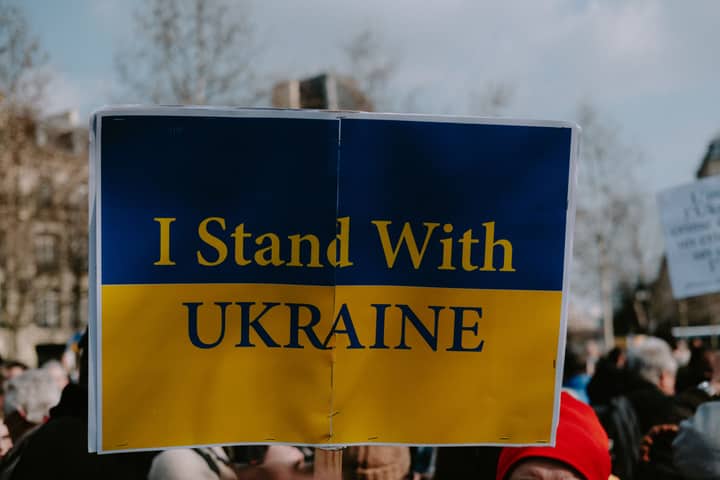 A protest image with a sign reading 'I Stand With Ukraine', showing solidarity and support.