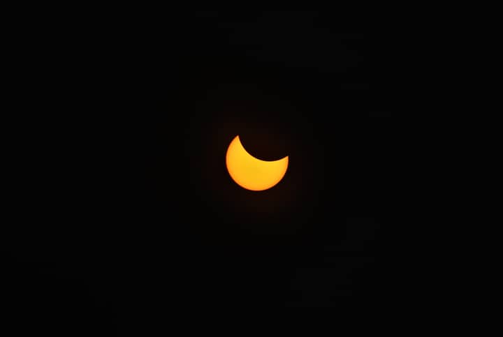 A stunning view of a partial solar eclipse captured against a pitch-black sky.