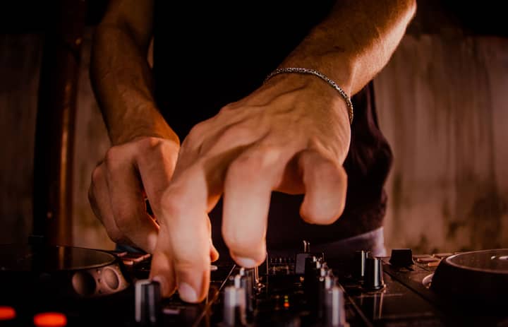 DJ's hands adjusting sound mixer knobs during a live performance.