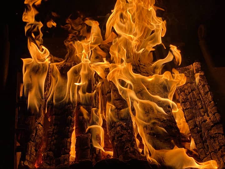 Close-up of intense flames consuming wooden logs, highlighting the warmth and energy of a blazing fire.
