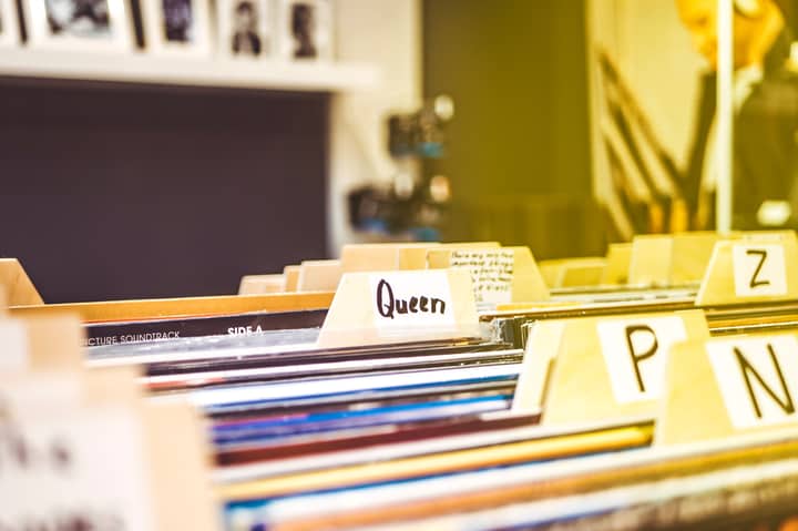 Close-up view of alphabetically organized vinyl records in an indoor music store setting.