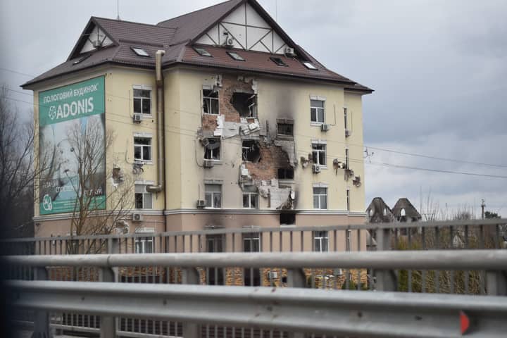 A war-torn residential building showing extensive damage in an urban setting.