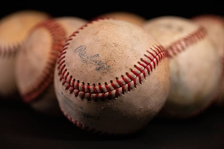 Focused close-up of old baseballs with visible stitching and texture against a dark background.