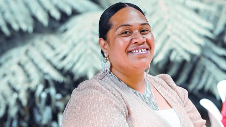 Portrait of a smiling woman wearing elegant jewelry against a natural outdoor background.