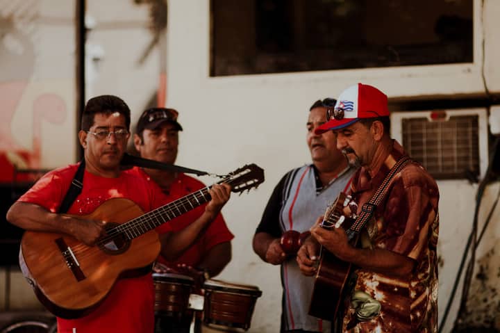 A group of street musicians playing guitars and percussion instruments in an outdoor setting.