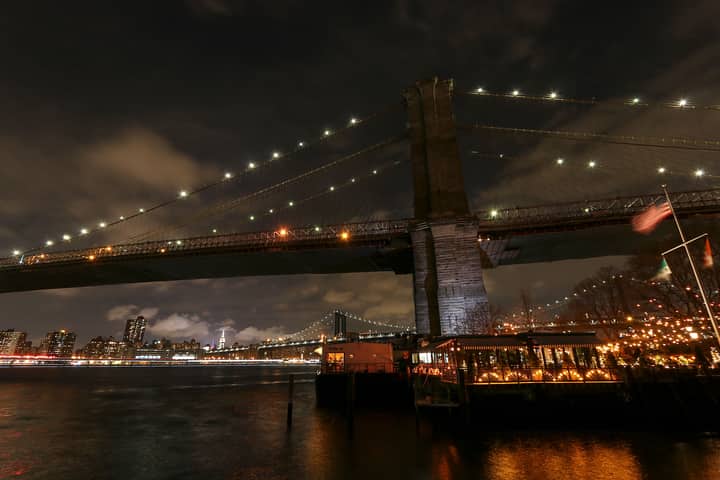 Captivating view of Brooklyn Bridge at night with New York City skyline in the background.
