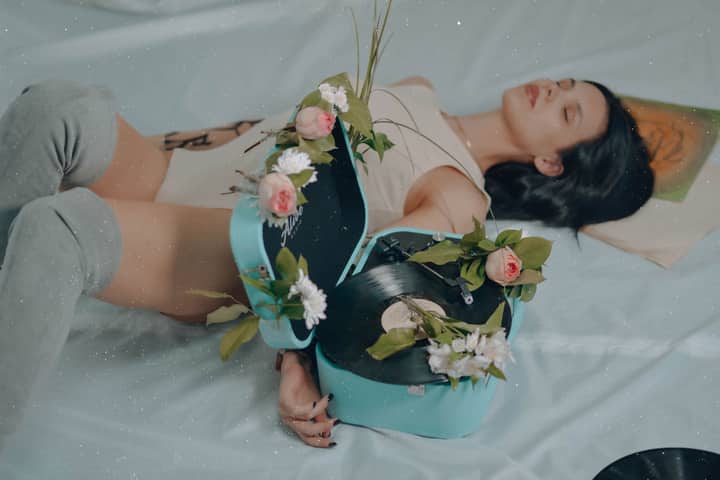 A woman posing with a vintage vinyl record player adorned with flowers.
