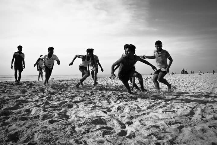 Energetic young boys playing on Thiruchendur beach, captured in dynamic black and white.