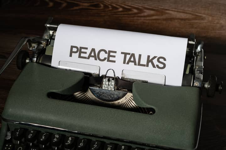 A classic typewriter displays the words 'Peace Talks', symbolizing communication and diplomacy.