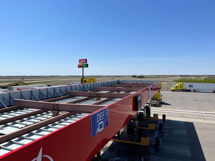Aerial view of a truck stop with gas station and parking lot under a clear blue sky.