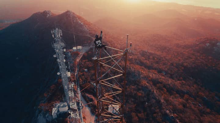 Adventurous person atop a communications tower at sunset in Mexico City, CDMX, Mexico.