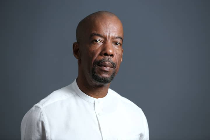 Portrait of a middle-aged African American man in a white shirt with a neutral background.
