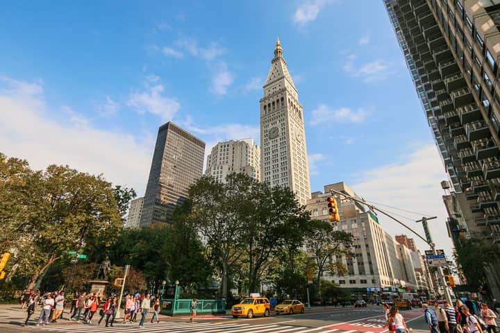 A lively street scene in Manhattan's Flatiron District with iconic architecture and busy pedestrians.
