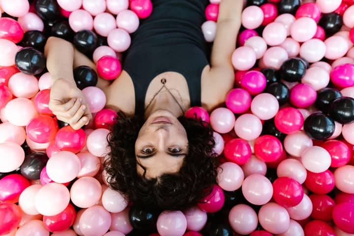 Upside-down portrait of a person surrounded by colorful plastic balls, offering a whimsical and playful feel.