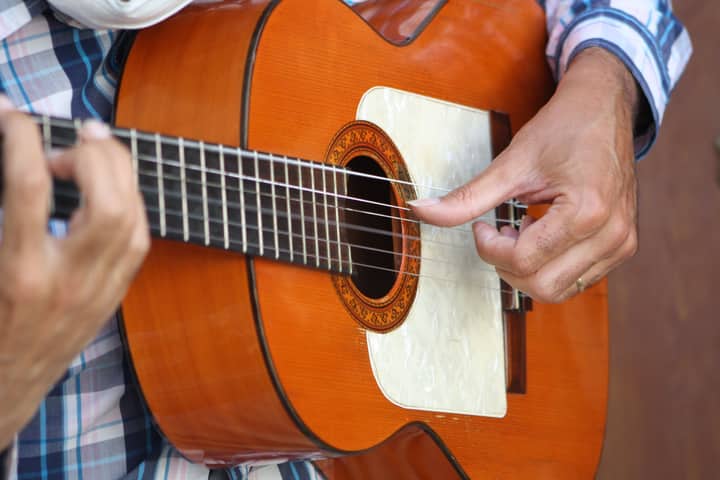 A detailed close-up of a flamenco guitarist's hands strumming a wooden guitar in Córdoba, Spain.