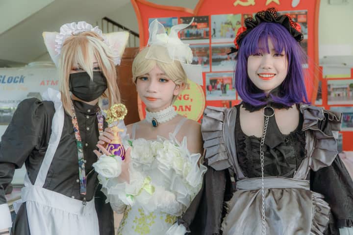 Three cosplayers in vibrant costumes and accessories pose for a photo, highlighting creativity and style.