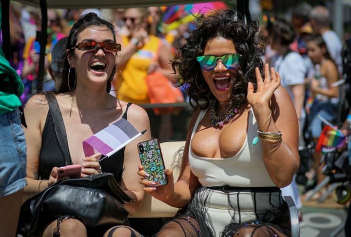 Two women joyfully participating in the colorful New York Pride Parade.