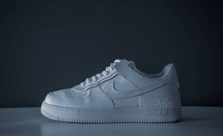 Minimalist image of a white sneaker on a dark background showcasing modern style.