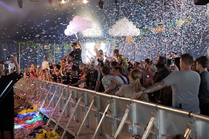 An enthusiastic crowd enjoys a confetti-filled indoor concert.