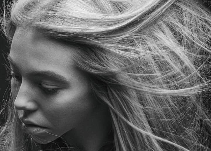 Black and white close-up portrait of a woman with wind-swept hair, capturing emotion and movement.