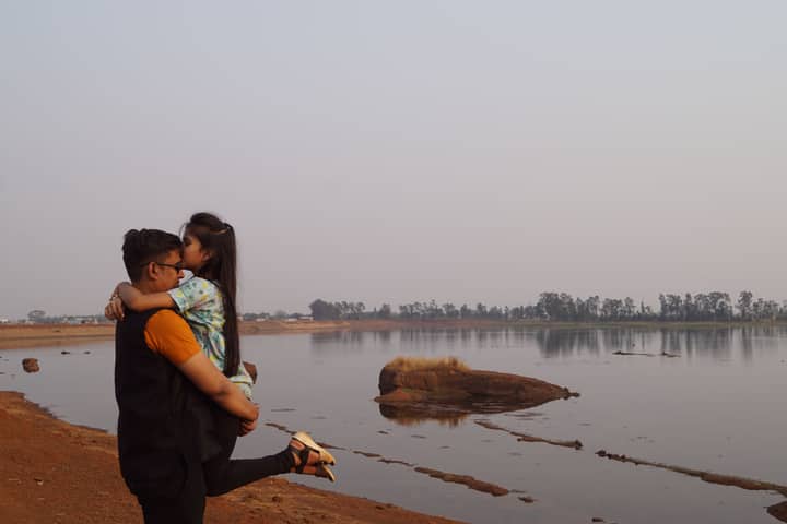 A romantic moment by the lakeside with a couple embracing and enjoying the serene natural surroundings.