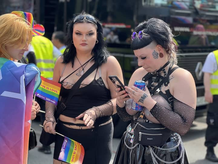 People celebrating Pride in Berlin with colorful clothing and flags.