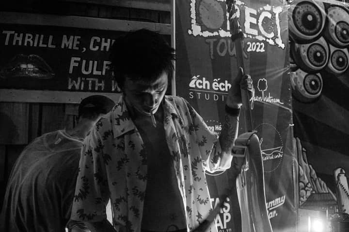 Tattooed guitarist in a monochrome setting with banners, captured in a moody, artistic vibe.