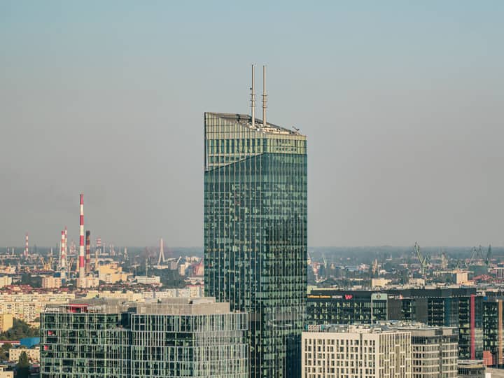 A striking view of a modern skyscraper amidst Gdańsk's cityscape, showcasing urban architecture.