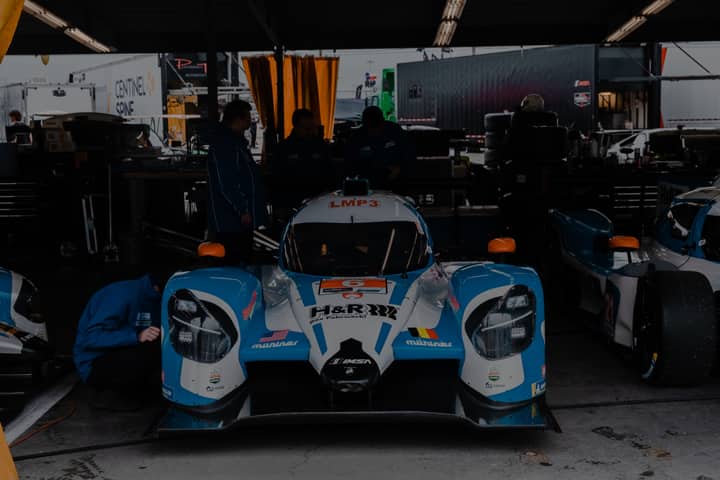 A high-performance race car undergoing preparation in a professional garage setting.