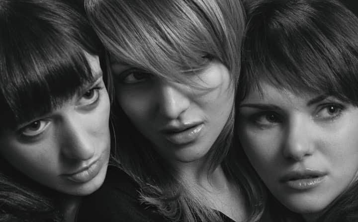 Black and white close-up portrait of three women showcasing different hairstyles, expressing various emotions.