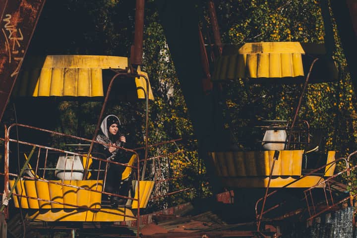 Eerie scene of an abandoned ferris wheel in Chernobyl featuring a lone woman.