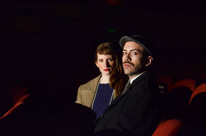 A man and woman sitting in a dimly lit theater, adding a vintage touch.