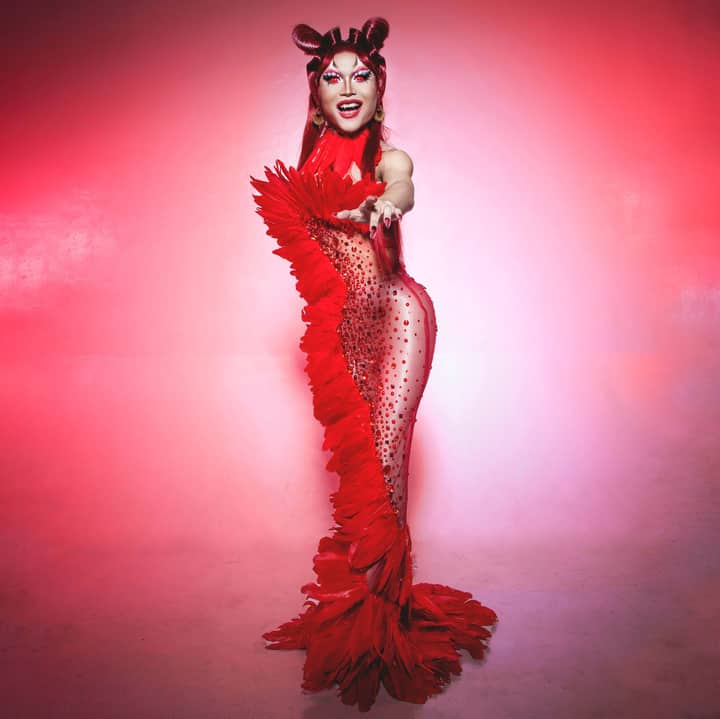 Full-body portrait of a woman in a stunning red costume with feathers, shot in studio.