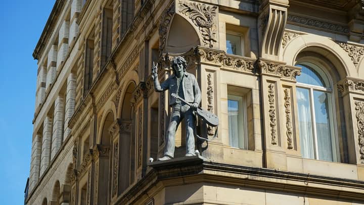 A detailed view of a musician statue on a historic building in Liverpool, England.