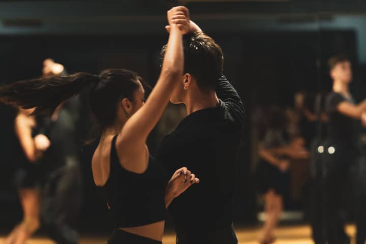 A couple elegantly performing tango inside a dance studio with onlookers.