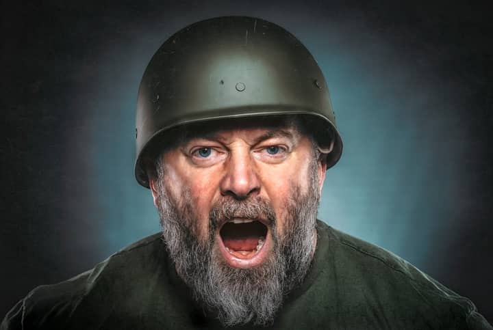 Intense portrait of a bearded man in a helmet shouting. Dramatic expression captured.